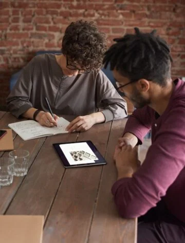 man wearing purple long sleeved shirt looking at the ipad 3184326